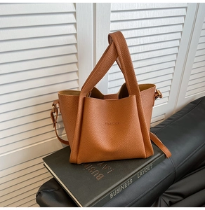Close-up of brown litchi grain bucket bag with FASHION embossed detail on book