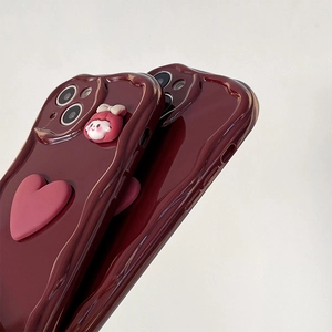 Detail of red wavy edge phone case with pink heart and cartoon bow charm for iPhone
