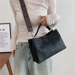 Detail of black geometric PU tote with colorful ethnic print wide strap on a model