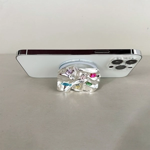 Detail view of a metallic phone grip stand with colorful rhinestones and wrinkled texture