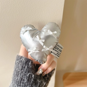Detail of silver heart phone grip featuring delicate white bows and a fabric brand label
