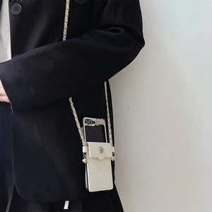 Detail of cream quilted phone case with gold camellia clasp and crossbody chain strap
