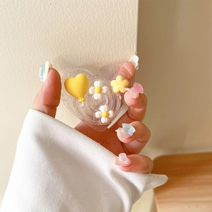 Gros plan du support téléphone cœur à paillettes avec ballon jaune et marguerites