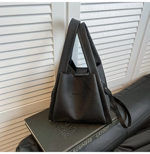 Detailed macro view of black lychee texture leather bucket bag with front pocket design
