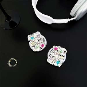 Detail of metallic pleated phone grip with colorful rhinestones on a dark background