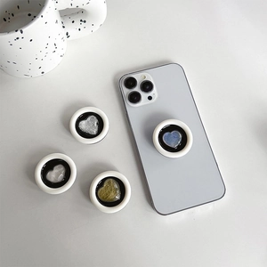 Detail of four heart-shaped phone grips with natural stone resin textures on white marble