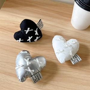 Macro detail of heart shaped fabric phone grips with bows in black, white, and silver
