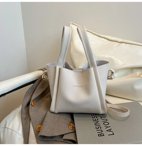 Detailed view of beige litchi pattern bucket bag with fashion logo on leather