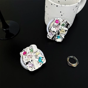 Macro detail of metallic silver phone grip base with sparkling colorful gemstones
