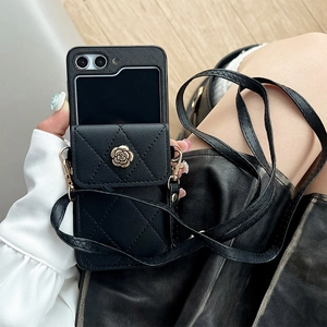 Detalle de funda acolchada negra con hebilla de camelia dorada y correa de hombro