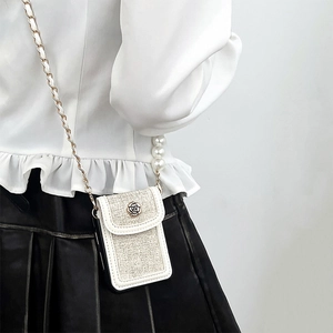 Detail of tweed crossbody phone case with metallic rose clasp and pearl chain strap