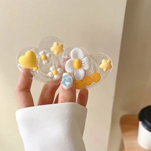 Détail d'un support de téléphone cœur pailleté avec des fleurs et des smileys