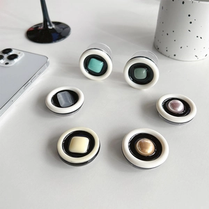Flat lay of six colorful round expandable phone grips on a minimalist white desk