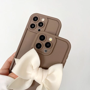 Vue détaillée de la coque en silicone marron avec un grand nœud en tissu blanc crème pour iPhone