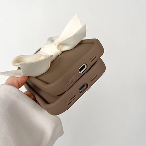 Gros plan d'une coque en silicone marron avec un grand nœud en satin blanc et découpes précises