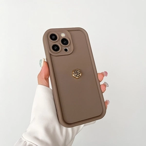 Détail de la coque en silicone marron mat avec un ornement de rose dorée en métal