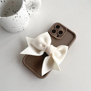 Détail de la coque iPhone marron avec un grand nœud en tissu couleur crème