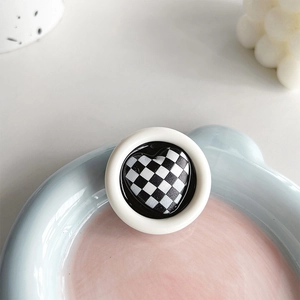 Close-up of minimalist black and white checkered heart phone grip on a round base