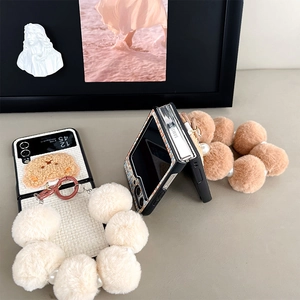 Detail of plush bear decoration and large colorful fur ball wrist strap on folding phone case