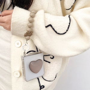 Detail of Galaxy Z Flip case with heart grip and bead lanyard featuring a bow