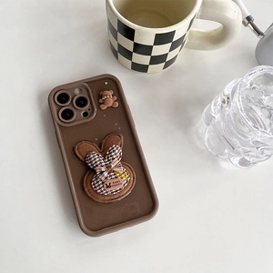 Dettaglio custodia iPhone marrone glitterata con coniglietto 3D, fiocco pied de poule e orso