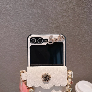 Detail of camellia logo and diamond smile decoration on beige leather folding phone case