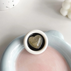 Detail of a round heart-pattern phone socket with gold texture on a pastel tray