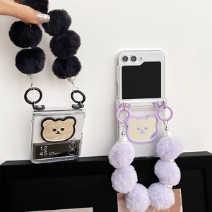 Close-up of clear folding case with bear mirror and plush ball lanyard in purple and black