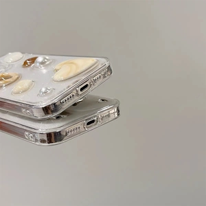 Detailed side view of iPhone case featuring 3D pearls, shells, and a large heart-shaped gemstone