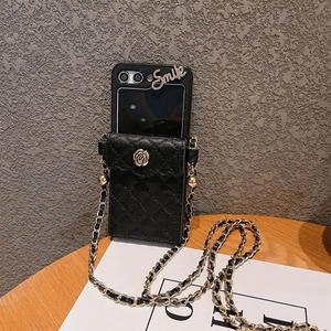 Crossbody phone bag with quilted black leather, gold chain, and camellia floral emblem