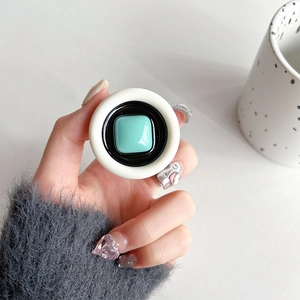 Detail of hand-held pop-socket featuring a round tricolor design and mint green square center