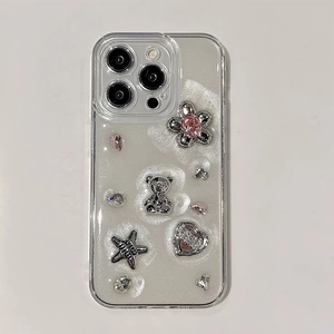Detail view of transparent iPhone case with silver bear, pink jewels, and star charms