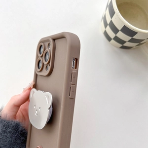 Detail view of coffee brown iPhone case with metallic silver bear-shaped phone grip