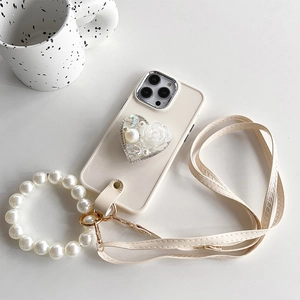 Detail of cream white phone case featuring a 3D rose heart stand and pearl wrist strap