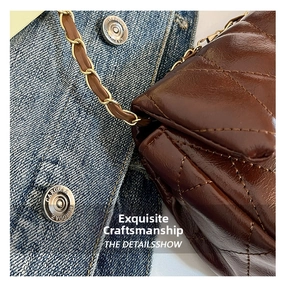 Detailed close-up of brown quilted leather bag with elegant metal chain strap and hardware