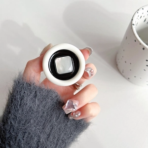 Detail of round b&w phone grip with pearl-like square inlay held by hand