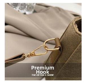 Macro detail of high-quality golden hardware hook on khaki crossbody bucket bag strap