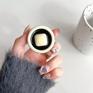 Detail of minimalist cream and black pop-up phone grip held against a soft grey sweater