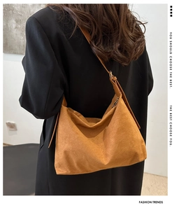 Detailed back view of a large brown suede crescent tote bag worn with a black blazer