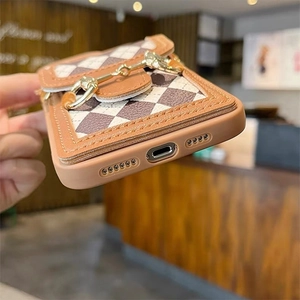 Nahaufnahme der braunen iPhone-Hülle mit Karomuster und goldener Vintage-Trensenschnalle
