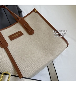 Détail d'un cabas en toile blanc cassé avec garniture en cuir brun et boucles dorées
