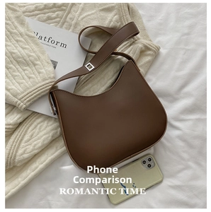 Size comparison of a dark brown crescent underarm bag next to a smartphone