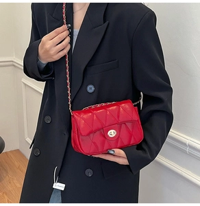 Detail of red quilted leather handbag featuring a gold turn-lock and chain strap