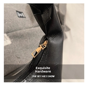 Detailed macro view of the golden metal zipper on a black lychee texture leather handbag