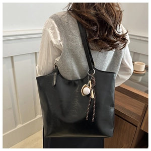Detail of a large black glossy faux leather tote bag with a baseball themed keychain