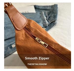 Detailed close-up of smooth gold metal zipper on a premium brown suede shoulder bag
