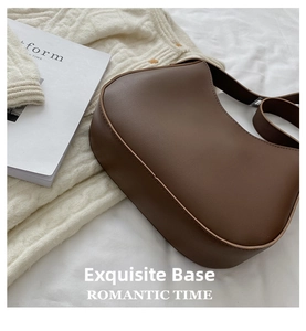 Detail of flat bottom and stitching on brown faux leather underarm bag on beige knitwear