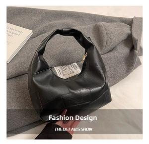 Detail showing woven leather texture and gold zipper of the black underarm handbag