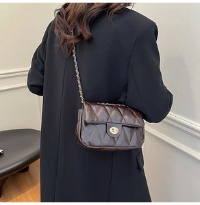 Detail of dark brown quilted crossbody bag with gold chain strap on model's shoulder