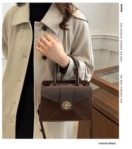 Detail of dark brown tote bag with gold petal buckle worn with a beige trench coat